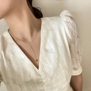 Gros plan du collier Y élégant en étoile dorée sur une robe en dentelle blanche