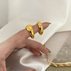 Close-up of thick gold-plated minimalist dome rings displayed on elegant white silk