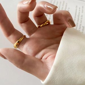Detailed view of two gold organic wavy rings on a finger with a glossy mirror finish