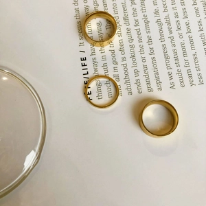 Close-up of three 18k gold plated minimalist titanium rings in various widths and textures