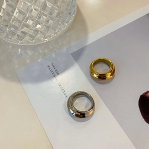 Detailweergave van dikke koepelringen in goud en zilver op een minimalistisch blad