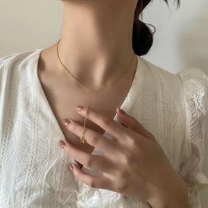 Détail d'un collier en Y doré avec pendentif étoile porté sur un haut en dentelle