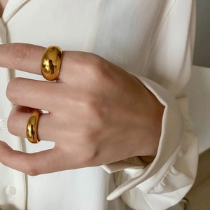 Close-up of chunky gold-plated domed rings showing mirror finish on a model