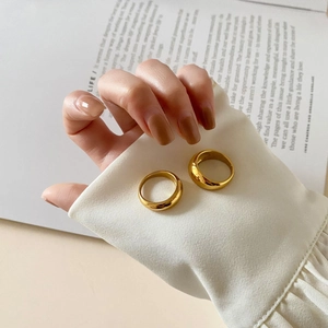 Detailed view of two polished gold rings stacked on a minimalist magazine background