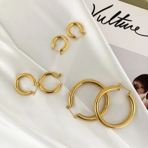Three pairs of polished gold hoop earrings in different sizes on white silk fabric