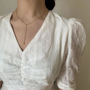 Détail d'un collier en Y doré minimaliste avec un pendentif étoile de mer sur un mannequin