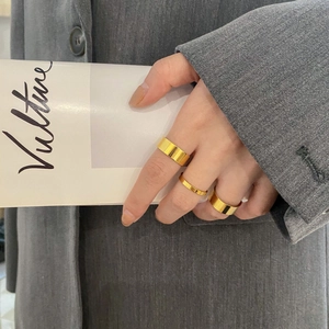 Set of three minimalist gold wide rings shown on a hand with a fashion magazine background