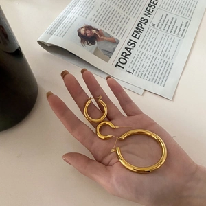 Detailed set of three gold hoop earrings in small to large sizes held in palm