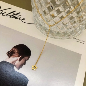 Collier en Y doré minimaliste avec pendentif étoile de mer sur un magazine de mode