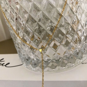 Vue macro détaillée du collier en Y doré minimaliste avec pendentif triangle sur verre