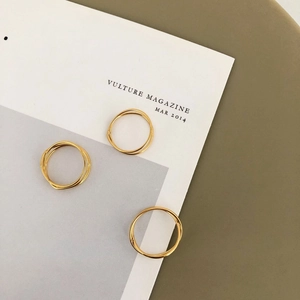 Close-up of three minimalist gold layered interlocking rings on a magazine surface