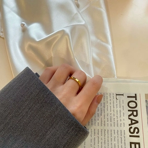 Polished gold wide band ring on model's hand with silk and pearls lifestyle detail