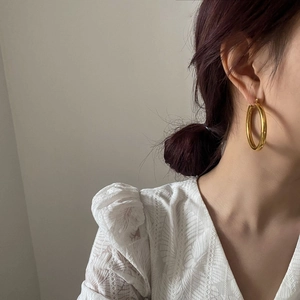 Close-up of large minimalist gold hoop earrings on model with polished mirror finish
