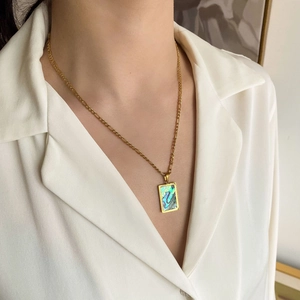 Dettaglio della collana Figaro dorata con ciondolo rettangolare in abalone su una modella