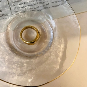 Detaillierte Draufsicht eines minimalistischen goldenen Siegelrings auf Glasschale