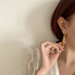 Close-up of a model wearing large minimalist golden hoop earrings with mirror finish