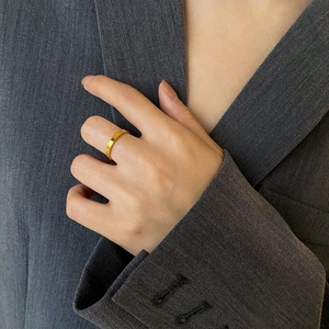 Close-up of minimalist gold plated square edge ring worn with professional business attire