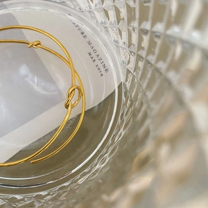 Minimalist champagne gold knot cuff bracelet featuring a sleek curved open C-shape design