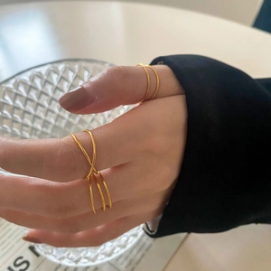 Detail shot of minimalist gold layered and crisscross rings with metallic texture
