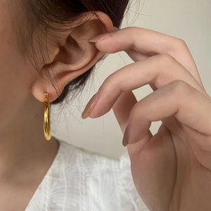 Close-up of minimalist gold hoop earring worn by a model for size and style display
