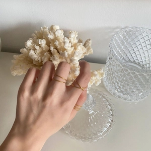 Close-up of minimalist layered golden rings with crisscross design on a hand