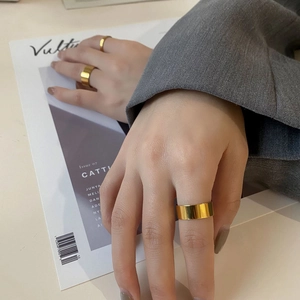 Close-up of minimalist wide gold metal rings worn with a grey suit for chic daily style