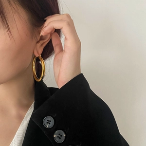 Close-up of chunky gold hoop earrings with mirror finish worn with black blazer