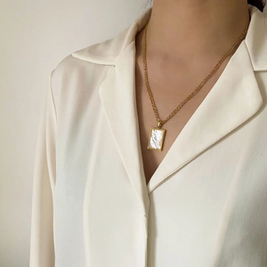 Dettaglio della modella con collana Figaro dorata e ciondolo rettangolare in conchiglia