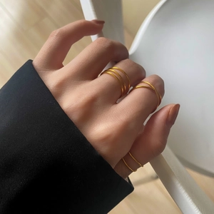 Close-up of minimalist layered gold rings with cross-wrap design on a model hand