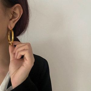 Detail of high-polish gold hoop earrings on model highlighting minimalist style