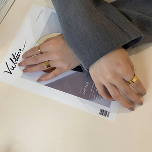 Close-up of minimalist wide gold-plated rings worn by a model in a stylish lifestyle setting