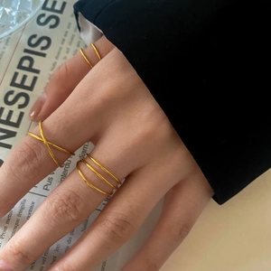 Detail of gold multilayered minimalist rings styled with a vintage crossed design