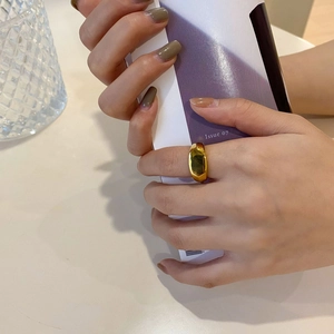 Nahaufnahme eines breiten, polierten goldfarbenen Edelstahlrings mit Facettendesign
