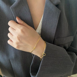 Detail of gold knot cuff bracelets on model's wrist with elegant minimalist design