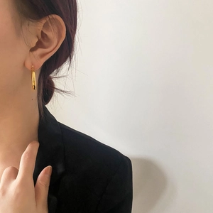 Close-up of minimalist thick gold hoop earrings with mirror finish on model