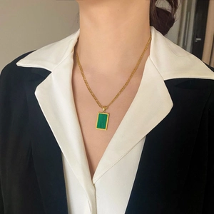 Dettaglio del ciondolo rettangolare in malachite su una sottile catena figaro dorata