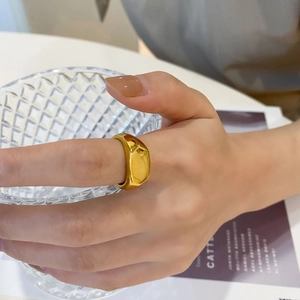 Detail eines breiten, polierten goldfarbenen Titanstahlrings mit unregelmäßigem Design