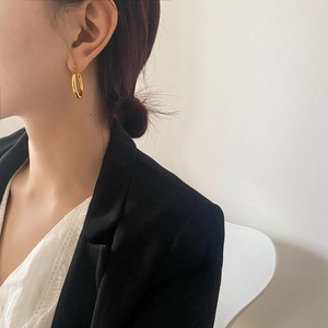 Minimalist gold hoop earrings worn by a model in a modern office-style look