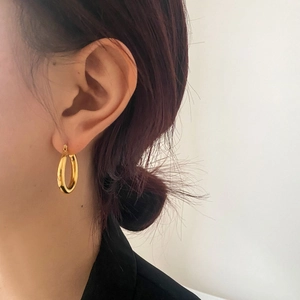 Close-up of polished gold hoop earrings on model for a minimalist fashion look