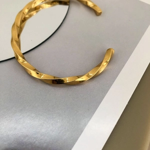 Nahaufnahme des goldenen Mobius-Armreifs mit eleganter Spiralstruktur und Glanzfinish