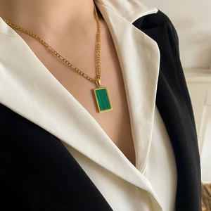 Dettaglio di una collana vintage dorata con ciondolo in malachite verde su modella