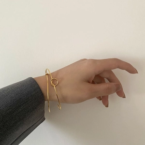 Minimalist gold knot open cuff bracelet worn by a model in professional office style