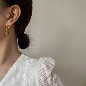 Close-up of elegant gold thick hoop earrings worn by a model in a lifestyle scene
