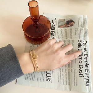 Detail of minimalist gold knotted cuff bracelet worn with elegant grey sleeve