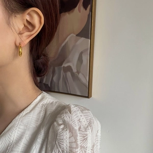 Elegant gold hoop earrings for women with minimalist metallic finish shown on model