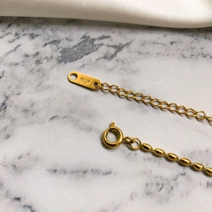 Macro detail of 18K gold bracelet extension chain with spring clasp and K18 tag