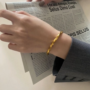 Detailansicht eines goldenen Mobius-Armreifs im Twist-Design mit eleganter Bürokleidung