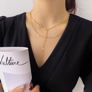 Détail d'un élégant collier double rangée dorée en Y avec paillettes sur un mannequin
