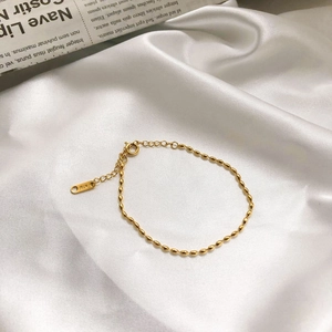 Close-up of golden oval bead bracelet with K18 tag on elegant white silk fabric