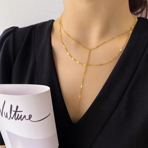 Détail d'un collier Y doré à deux couches avec des maillons carrés portés sur noir